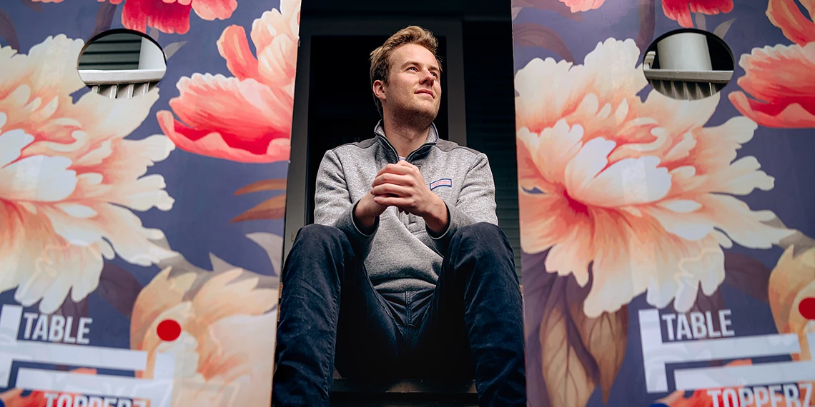 Senior business student Jack Githens sits between custom-designed cornhole game sets.